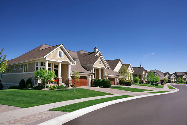 A row of suburban houses with neatly manicured lawns on a sunny day.