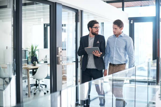 Two businessmen discussing real estate trends while walking through a modern office in Dubai.