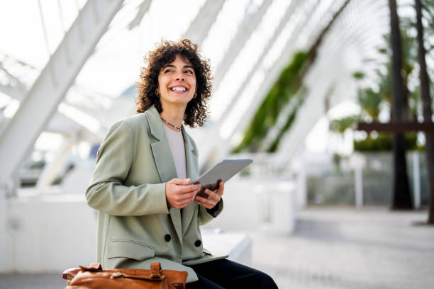 A woman smiling while holding a tablet, preparing to buy property in Dubai.