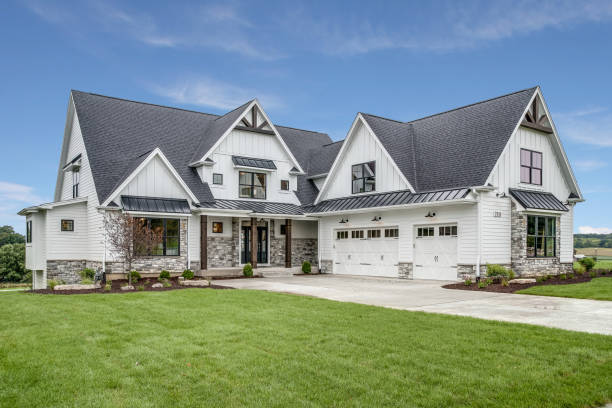 A large, modern white house with a dark roof and a well-manicured lawn.